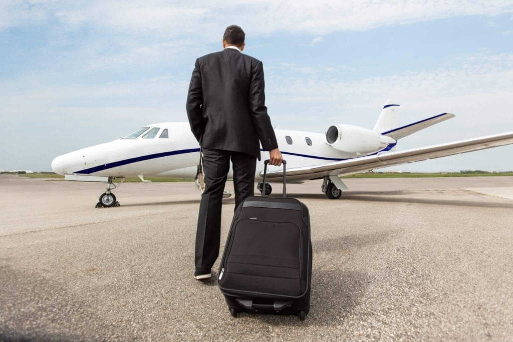 A man in a suit walking towards a small plane for an airport transfer.