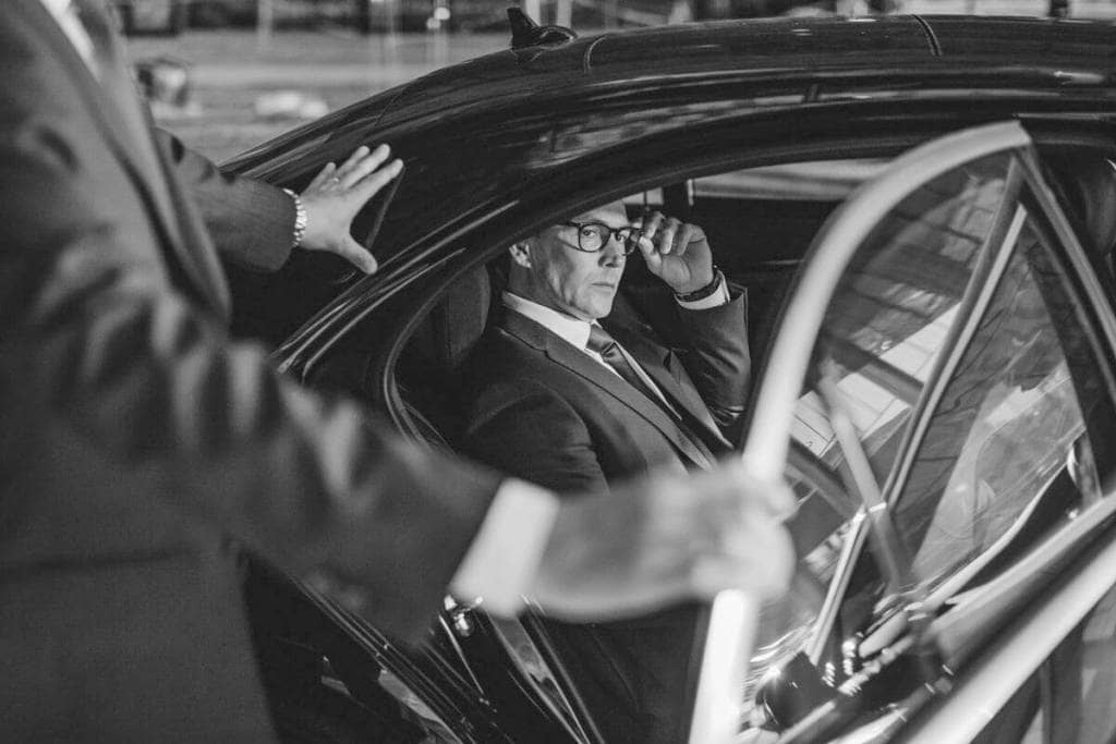 A black and white photo of a man getting out of a car.