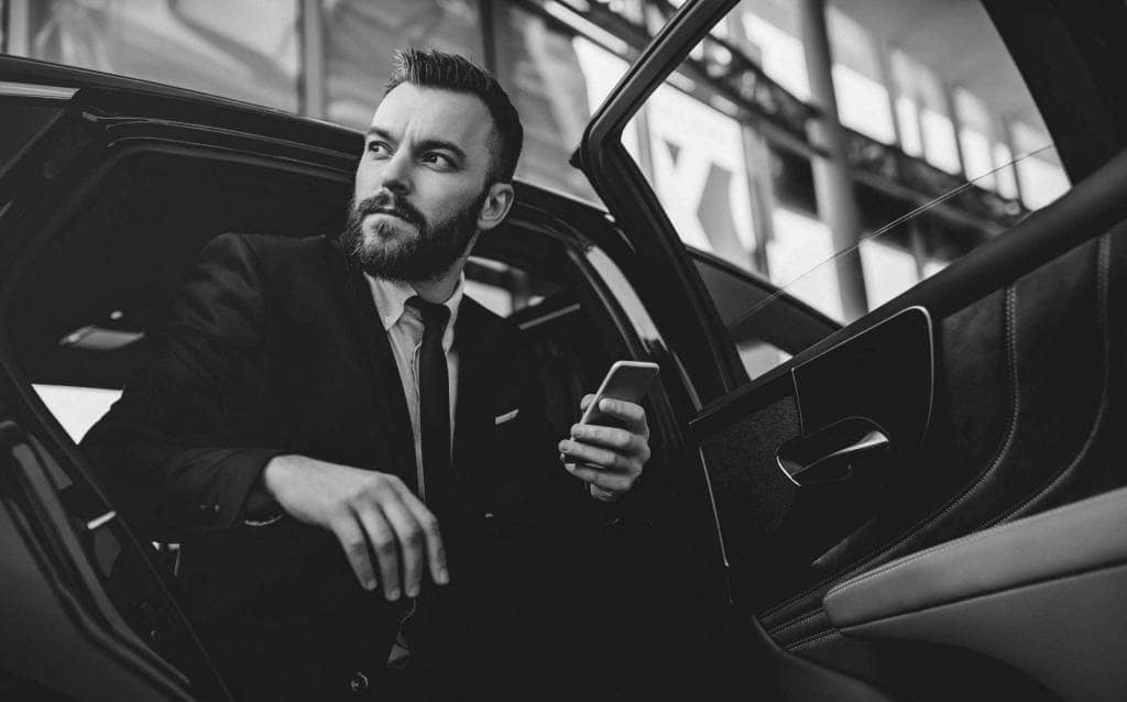 A man in a suit is sitting in the back seat of a car.