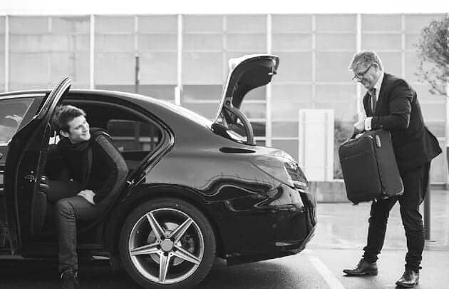 Black and white photo of a man opening the door of a mercedes benz.