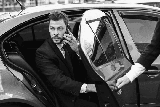 A man and woman talking on the phone in a car.