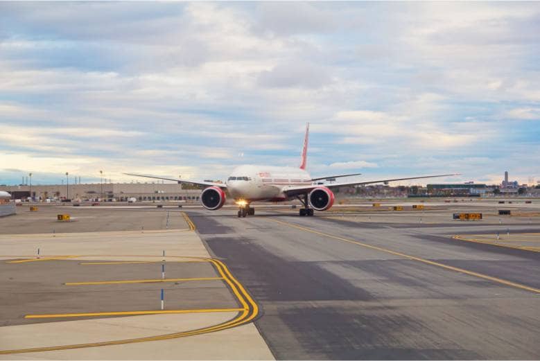 A red and white airplane on a runway at Newark Airport.