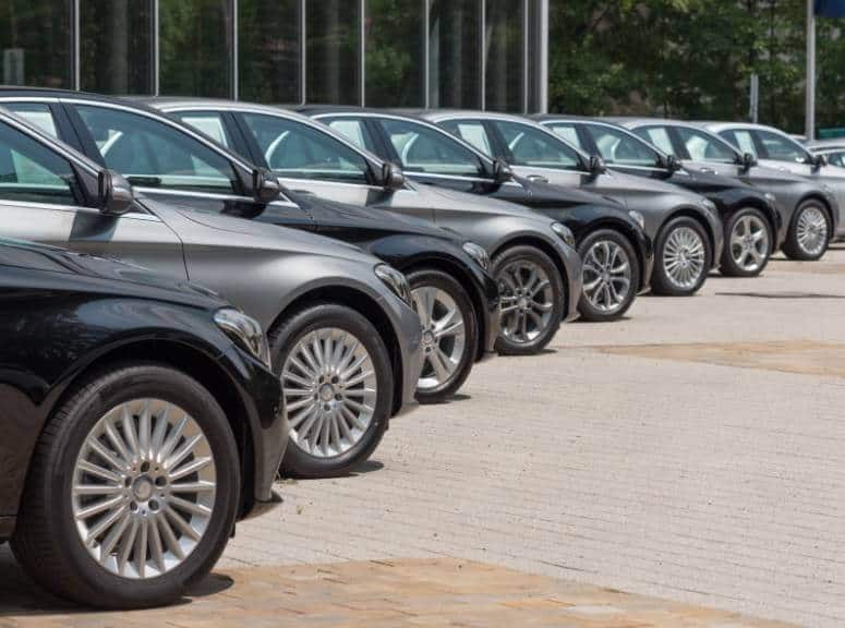 A row of luxurious Mercedes Benz cars parked in front of a building, offering dependable car service from NJ to Newark Airport.
